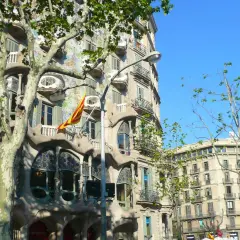 La Casa Batlló, joya modernista, luce su fachada ondulante y colorida bajo el sol. Una bandera catalana ondea, celebrando Sant Jordi.