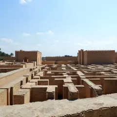 Ruinas de ladrillo de la antigua Babilonia, un laberinto de muros bajo un cielo azul.