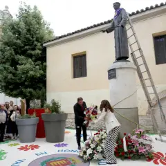 Ofrenda floral a San Pedro Regalado. Un hombre y una mujer colocan flores ante la estatua.