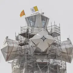 La torre de Jesús de la Sagrada Familia, cubierta con lonas y rodeada de andamios, ondea las banderas de Cataluña y el Vaticano.
