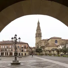 Plaza de Santo Domingo de la Calzada, con su imponente catedral y edificios históricos. Un peregrino con paraguas cruza la plaza empedrada.