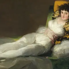 La venus del espejo, una mujer recostada en un diván, viste un traje blanco y mira al espectador con una expresión seductora.
