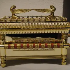 Réplica dorada del arca de la alianza, con querubines alados en la tapa y detalles ornamentales.