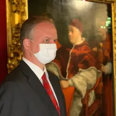 Hombre con mascarilla frente a un retrato del papa León X.