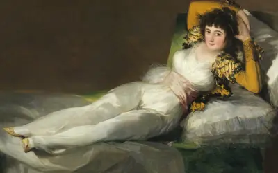 La venus del espejo, una mujer recostada en un diván, viste un traje blanco y mira al espectador con una expresión seductora.