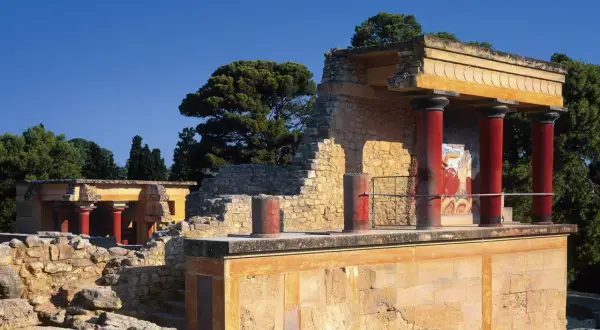 Ruinas del palacio de Cnosos con sus icónicas columnas rojas y un fresco de toro.