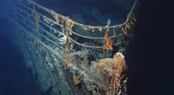 Proa del Titanic, una de las **titanic fotos reales**. Corrosión y vida marina cubren la barandilla oxidada en las profundidades del océano.