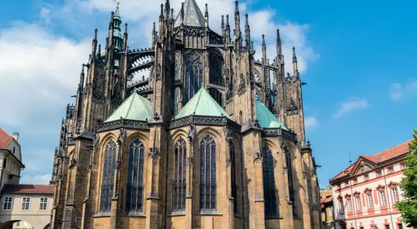 Imponente catedral gótica con sus torres y arcos detallados, bajo un cielo azul con nubes.