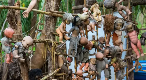 En la Isla de las Muñecas, muñecas viejas y rotas cuelgan de árboles y estructuras, creando una escena espeluznante.