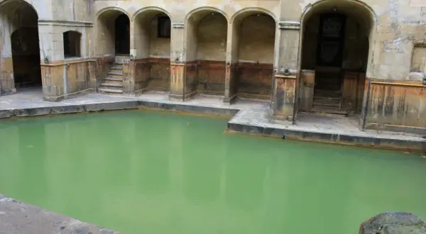 Las termas romanas, con su piscina de agua verde y arcos de piedra, evocan un pasado de baños y relajación.