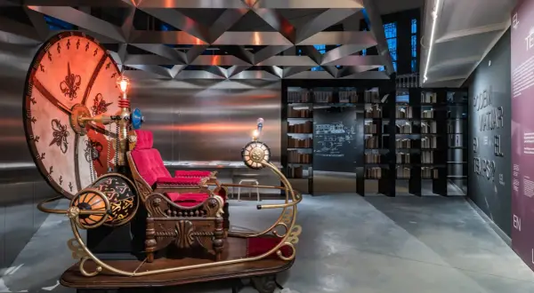 Máquina del tiempo inspirada en H. G. Wells, con asiento de terciopelo rojo y detalles dorados, lista para viajar.