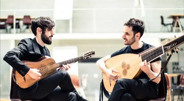 Dos músicos interpretan música renacentista, uno con guitarra barroca y otro con laúd, evocando la obra de Luis de Narváez.