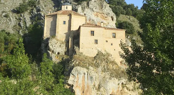 Edificio de piedra en un acantilado, rodeado de vegetación. Podría ser el lugar dónde nació Antonio Machado.