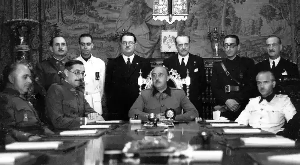 Luis Alarcón de la Lastra, rodeado de militares y civiles, en una reunión formal.