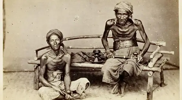 Dos hombres demacrados, víctimas de la guerra del opio, sentados con pipas de opio.