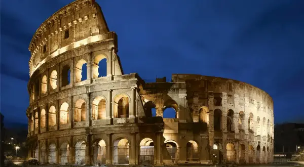 El Coliseo Romano, un ícono de la arquitectura antigua, iluminado bajo el cielo nocturno.