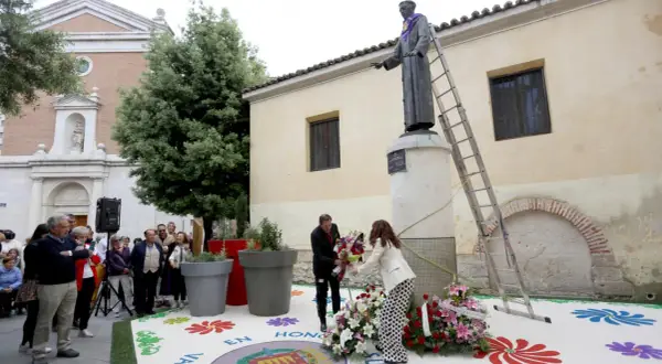 Ofrenda floral a San Pedro Regalado. Un hombre y una mujer colocan flores ante la estatua.