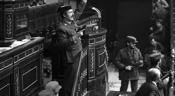 Un militar con pistola en mano, saludando, en el Congreso durante el golpe de estado de Tejero. Soldados armados observan.