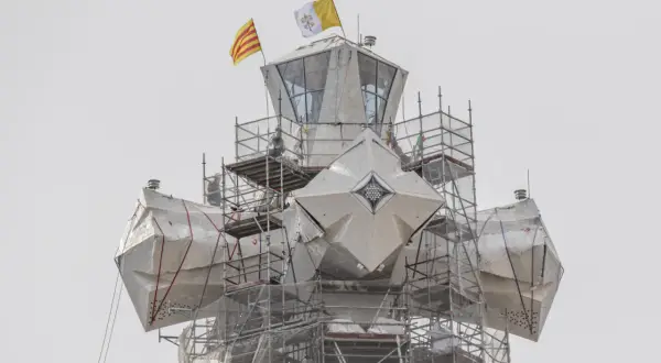La torre de Jesús de la Sagrada Familia, cubierta con lonas y rodeada de andamios, ondea las banderas de Cataluña y el Vaticano.