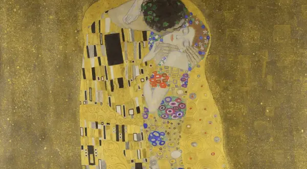 El beso de Gustav Klimt: una pareja abrazada en un campo dorado, ella con flores en el pelo, él con una corona de hojas.