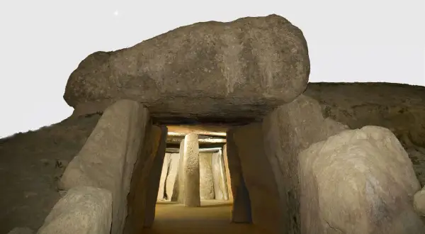 Entrada al dolmen de Menga, un túnel megalítico con pilares de piedra y una gran losa cubriendo la entrada.