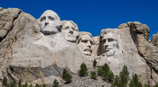 Las caras de cuatro presidentes de EE.UU. talladas en el **Monte Rushmore**, bajo un cielo azul intenso.