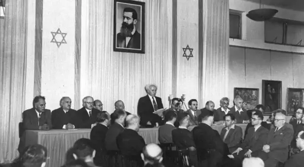 Hombres en traje asisten a un evento histórico, la creacion del estado de Israel, con la bandera israelí y un retrato de Theodor Herzl.