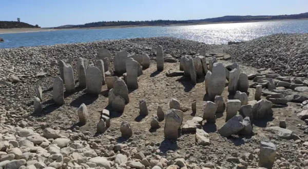 El dolmen de Guadalperal emerge de las aguas bajas, un círculo de piedras ancestrales bajo un cielo azul.