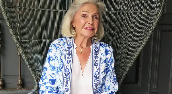 Beatriz de Orleans Borbón, con su elegante chaqueta floreada, sonríe sentada en un sillón de mimbre.