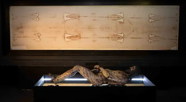 La sabana santa de Turín, con la imagen de un hombre crucificado, se exhibe junto a una figura que representa su cuerpo.