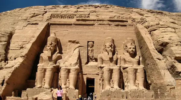 Gigantescas estatuas de Ramsés II flanquean la entrada del templo de Abu Simbel, Egipto. Un pequeño grupo de turistas admira la magnificencia de esta maravilla antigua.