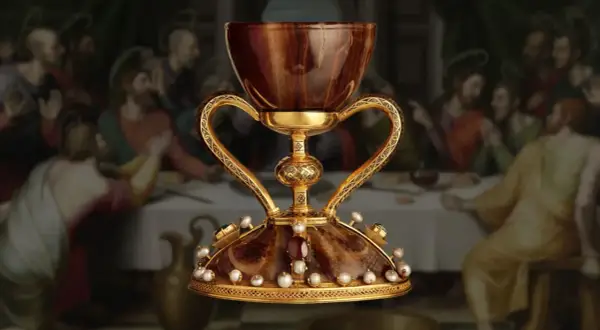 El cáliz dorado, adornado con perlas y gemas, evoca la búsqueda del santo grial donde está. Detrás, la Última Cena.