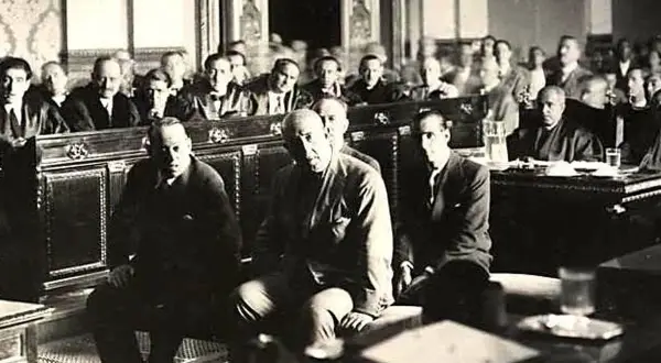 Hombres sentados en una sala, uno de ellos es José Sanjurjo y Prieto, en un evento histórico.