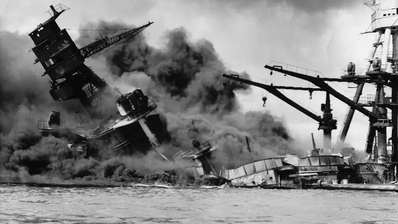 Barcos en llamas y humo denso tras el ataque a Pearl Harbor. Grúas industriales intentan ayudar en la devastación.