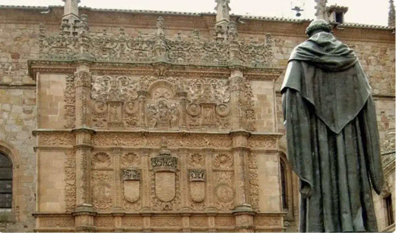 Estatua de Francisco de Vitoria frente a la fachada plateresca de la Universidad de Salamanca, con su detallada ornamentaci&oacute;n.