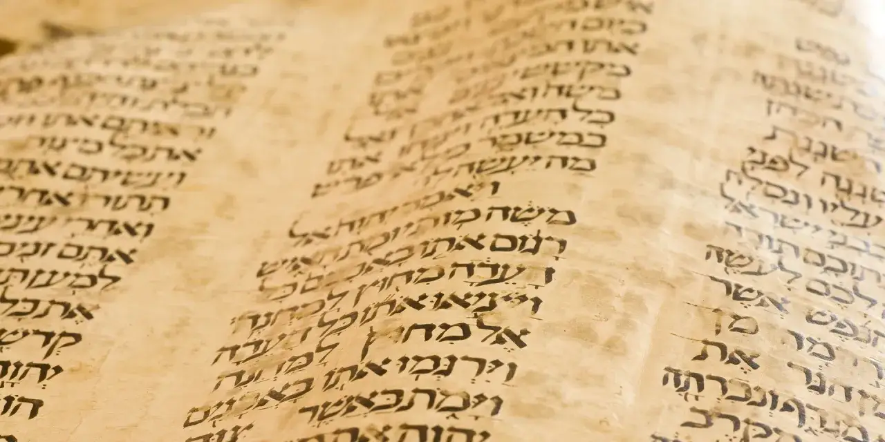 Detalle de un pergamino antiguo con escritura hebrea, que nos recuerda qu&eacute; es la Biblia y su antig&uuml;edad.