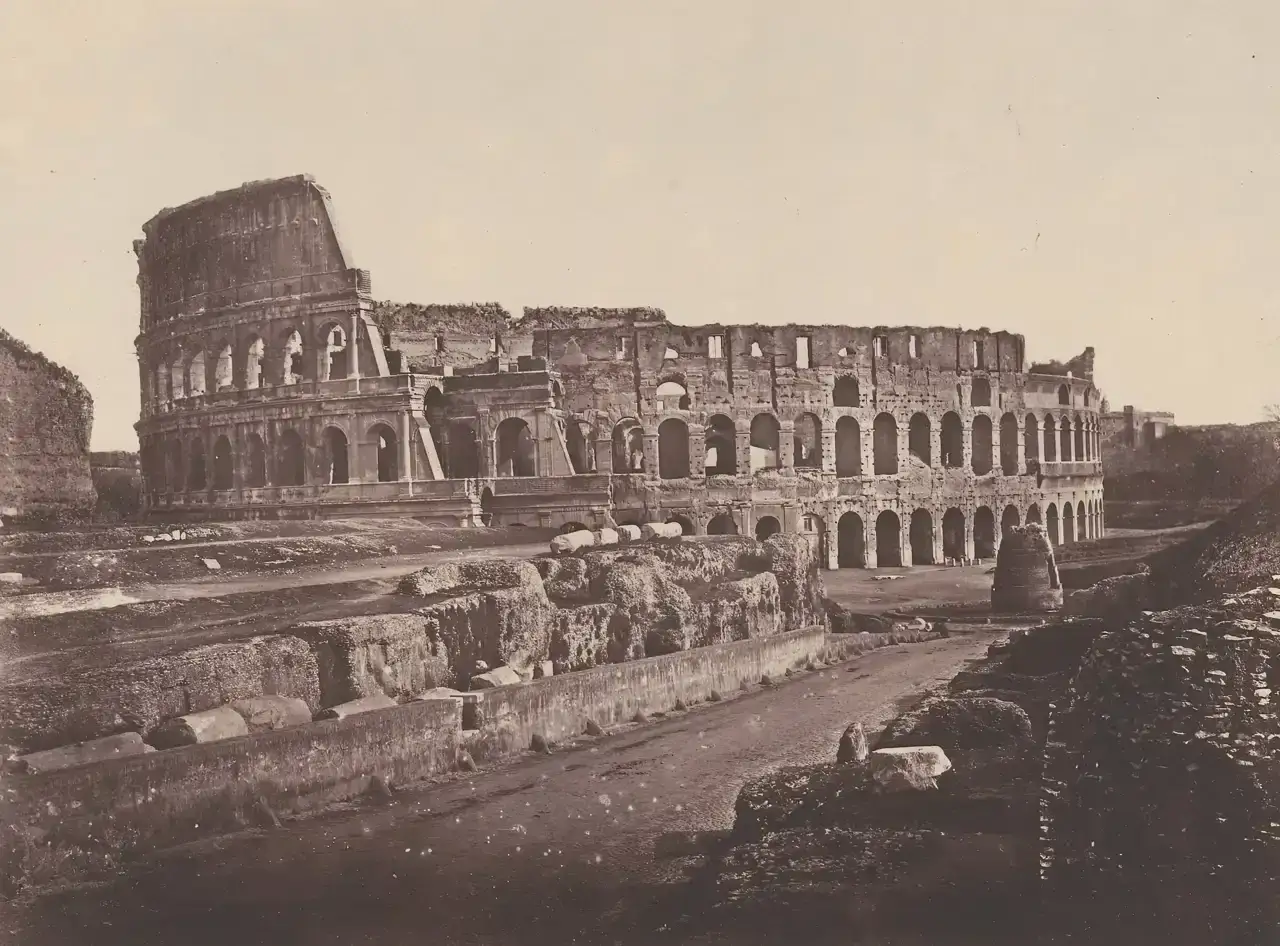 El coliseo romano antes y después: ruinas de un anfiteatro antiguo, con arcos y muros derruidos, evocando su pasado glorioso.