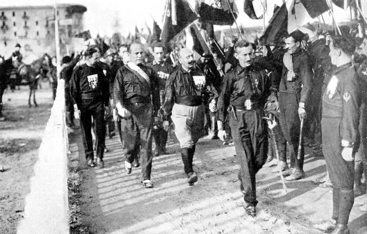 Mussolini, con uniforme negra y banda, lidera una marcha. Este evento es clave para entender como llego Mussolini al poder.