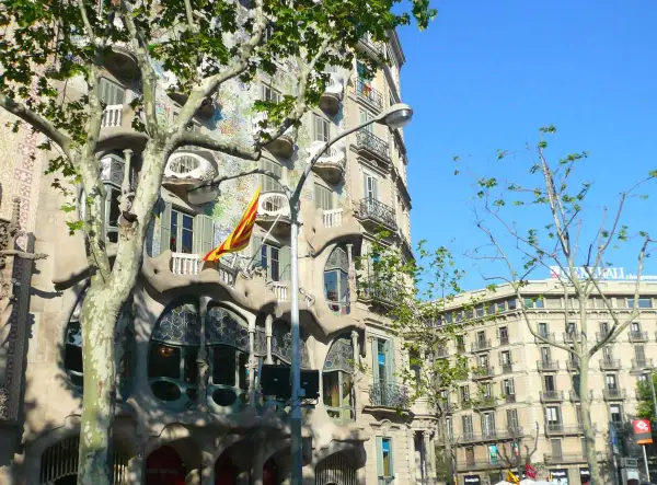 La Casa Batlló, joya modernista, luce su fachada ondulante y colorida bajo el sol. Una bandera catalana ondea, celebrando Sant Jordi.