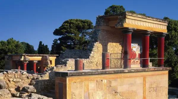 Ruinas del palacio de Cnosos con sus icónicas columnas rojas y un fresco de toro.