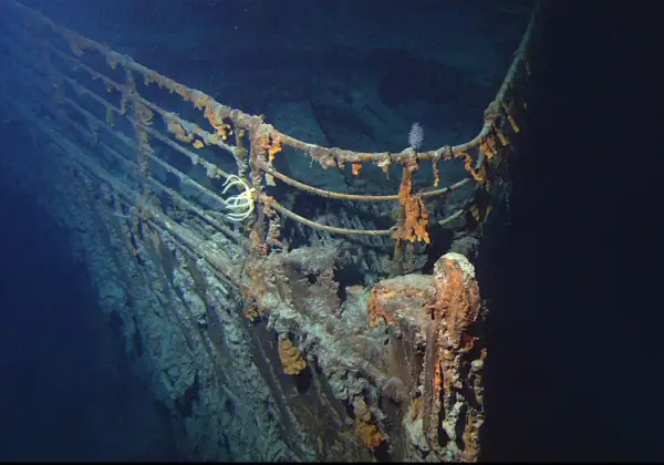 Proa del Titanic, una de las **titanic fotos reales**. Corrosión y vida marina cubren la barandilla oxidada en las profundidades del océano.