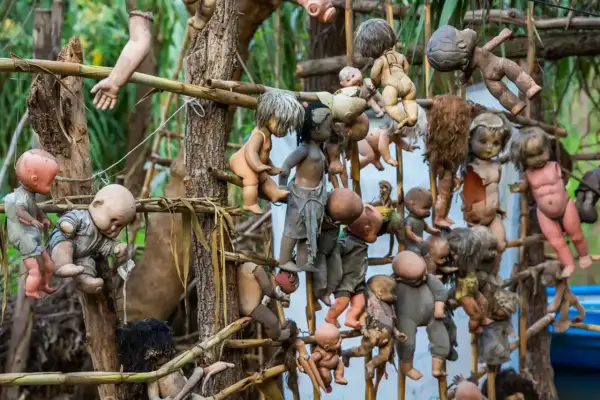 En la Isla de las Muñecas, muñecas viejas y rotas cuelgan de árboles y estructuras, creando una escena espeluznante.