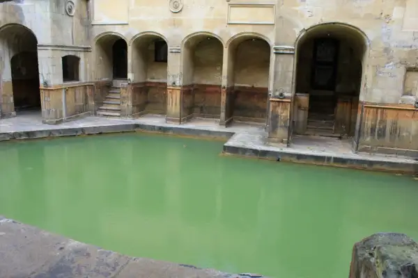 Las termas romanas, con su piscina de agua verde y arcos de piedra, evocan un pasado de baños y relajación.