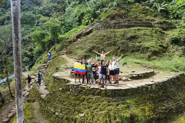 Grupo de turistas celebra en la **ciudad perdida Colombia**, rodeados de ruinas ancestrales y exuberante vegetación.