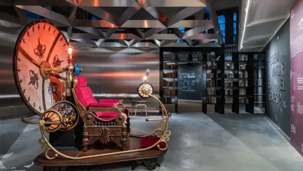 Máquina del tiempo inspirada en H. G. Wells, con asiento de terciopelo rojo y detalles dorados, lista para viajar.