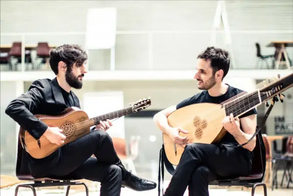 Dos músicos interpretan música renacentista, uno con guitarra barroca y otro con laúd, evocando la obra de Luis de Narváez.