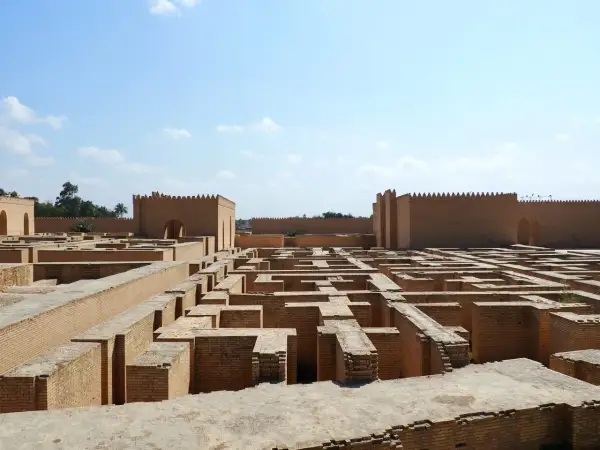 Ruinas de ladrillo de la antigua Babilonia, un laberinto de muros bajo un cielo azul.