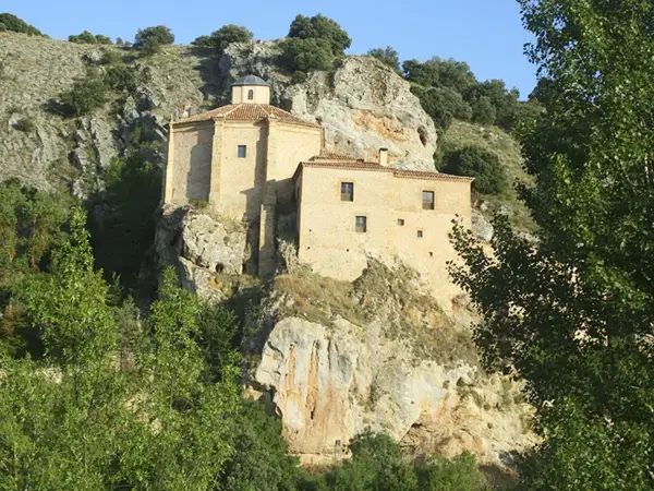 Edificio de piedra en un acantilado, rodeado de vegetación. Podría ser el lugar dónde nació Antonio Machado.