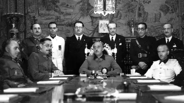 Luis Alarcón de la Lastra, rodeado de militares y civiles, en una reunión formal.