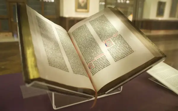 Un antiguo libro abierto, que podría ser la biblia, con páginas llenas de texto y decoraciones.